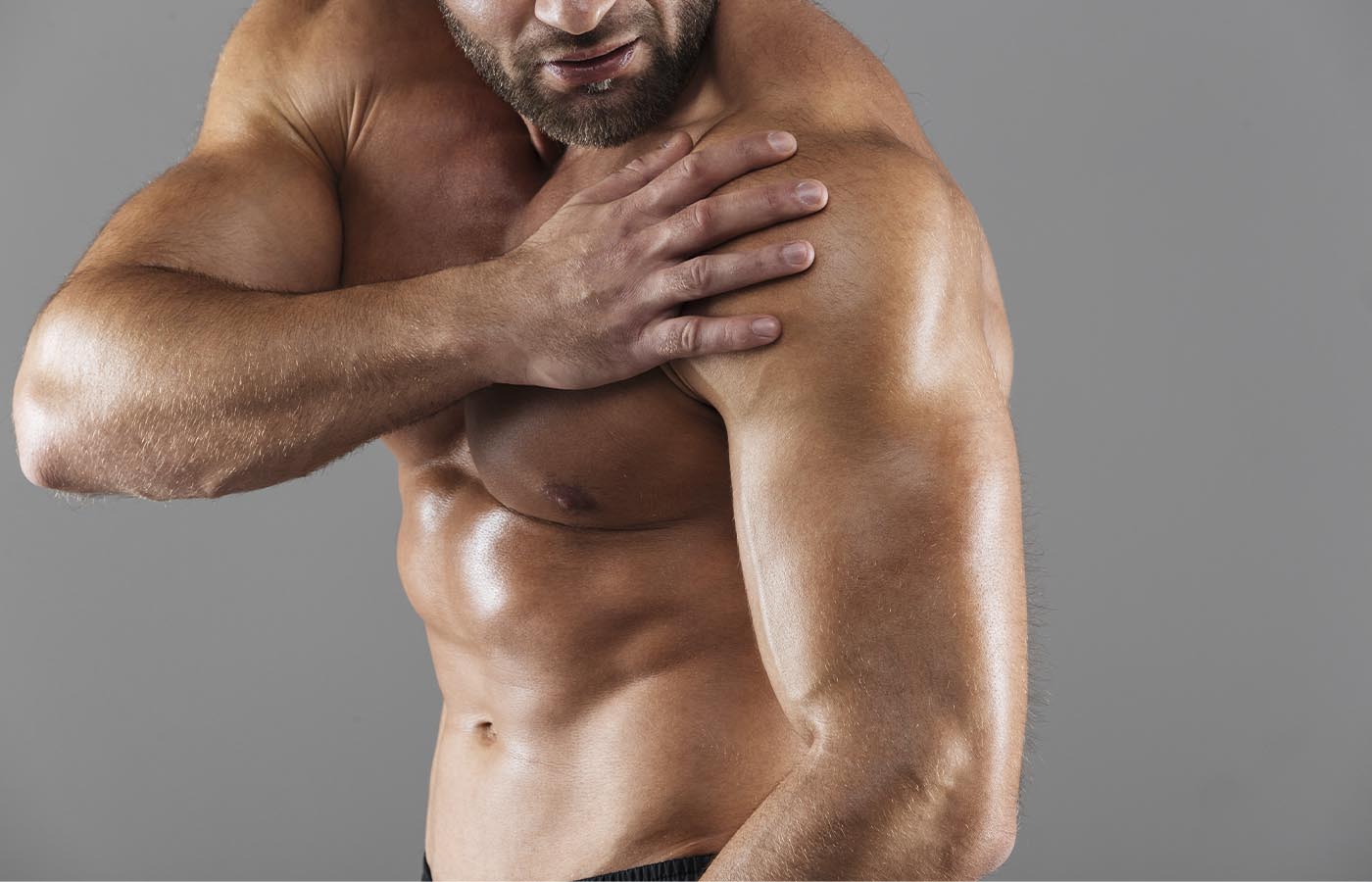 An athletic male rubbing his shoulder